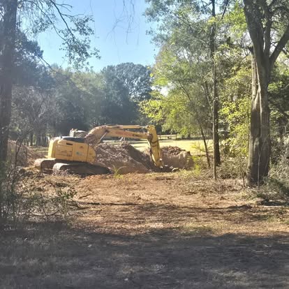 Excavator digging pond area during land clearing project