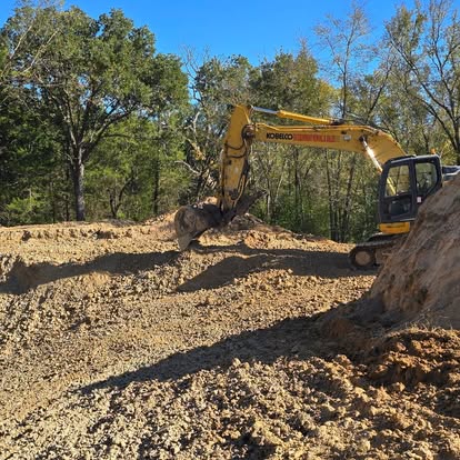 Excavator grading gravel lot for site preparation project