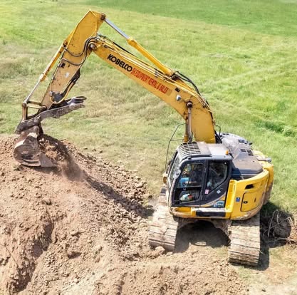 Excavator trenching soil during land development project