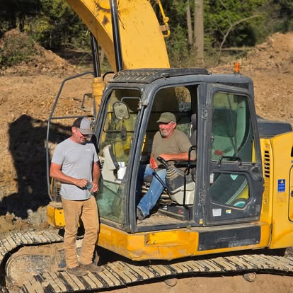 Crew members beside excavator during excavation project