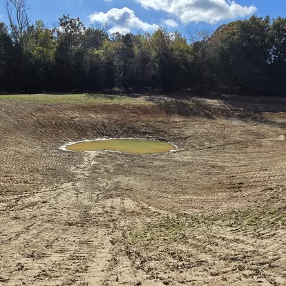 Newly constructed pond with water at center of cleared land
